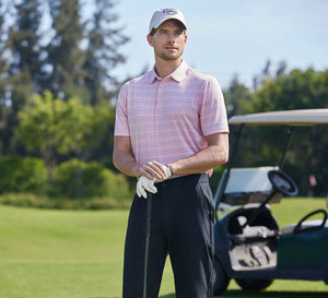 Man in a Stylish Stripe Jersey Golf Polo standing on the golf course, holding a golf club.