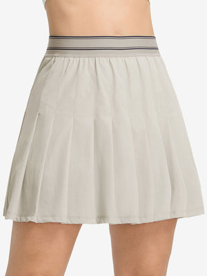 Front lower body shot of model wearing oyster gray women's moisture-wicking athletic tennis skirts