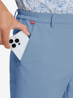 Close-up detail showing phone being placed in the pocket of misty blue thermal water repellent fleece dress pants