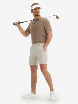 Full-body front view of model with a golf club wearing the light brown ventilated pique performance polo on the course