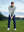 Model on grass under blue sky, leaning on golf club, wearing quarter zip melange pullover in lunar rock melange.