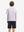 Back half-body view of youth wearing white pizza performance print boys golf polo, showing rear design